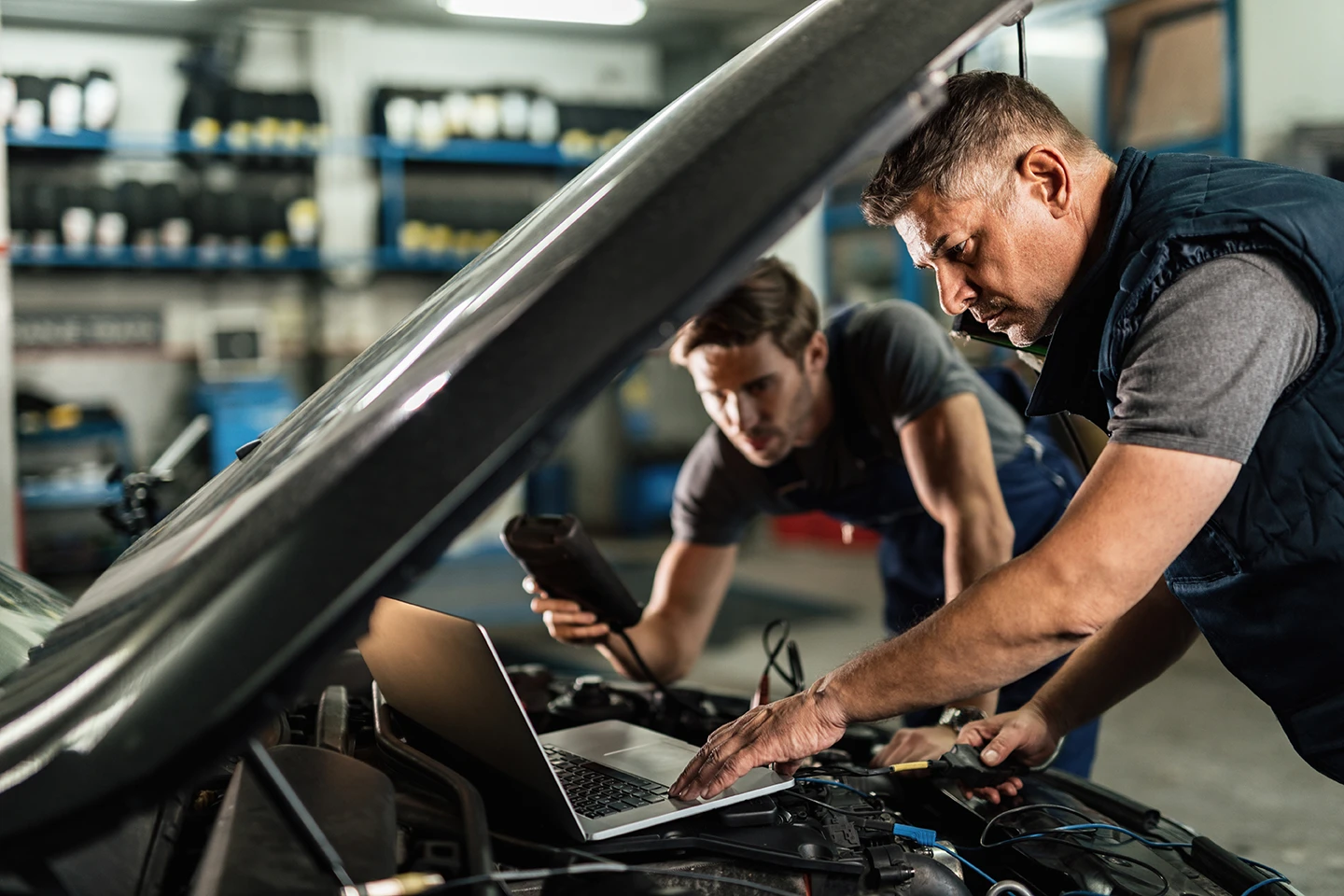 auto mechanic using laptop cooperating with coworker while doing car diagnostic repair shop kopie